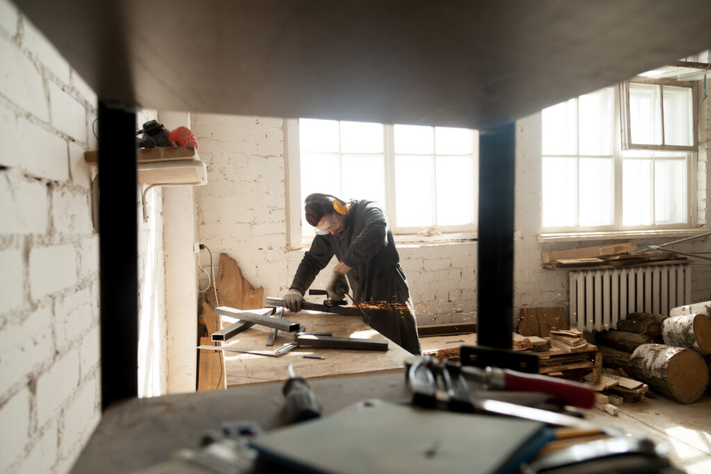 manual worker grinding metal steel objects in workshop with tool
